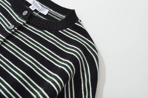 Detailed close-up of striped knit cardigan collar with black ribbing and brand label