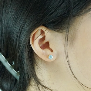 Pendiente clásico de oro de 18K con circonita azul claro puesto en la oreja