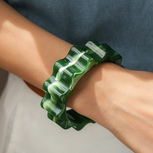 Dettaglio di un bracciale in resina con bordi ondulati e texture marmo verde indossato