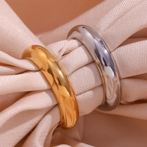 Polished gold and silver minimalist stainless steel rings on soft pink fabric