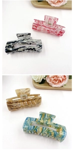 Detail of four large marble-patterned acrylic hair claws in assorted vibrant colors