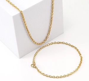 Detail of gold chain necklace and bracelet set with lobster clasp on white background