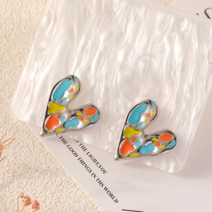 Macro detail of heart-shaped earrings with colorful enamel oil on a ripple acrylic base