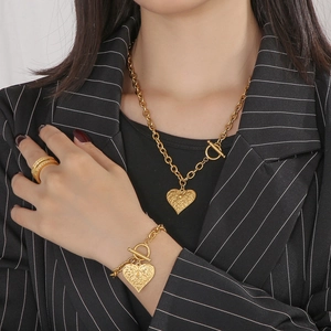 Macro shot of gold heart pendant jewelry set with multi-layer ring on model