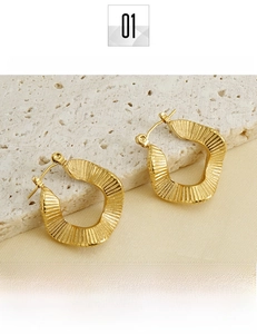 Macro detail of 18K gold plated titanium steel hoop earrings with wavy texture