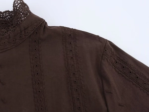 Detailed close-up of dark brown top featuring delicate lace collar and floral embroidery