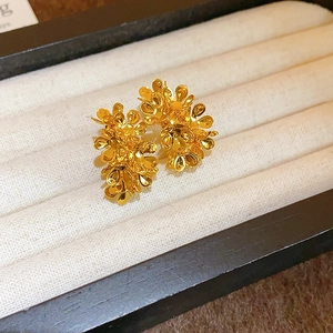 Gros plan de boucles d'oreilles dorées en forme de fleurs sur un plateau à bijoux en velours