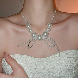 Elegant pearl necklace with woven bow pendant shown on model neck for a graceful style