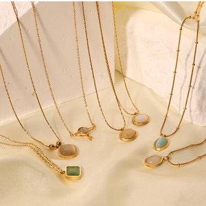 Detail of gold titanium necklaces with cat-eye stones, pearls and smile charms on silk cloth