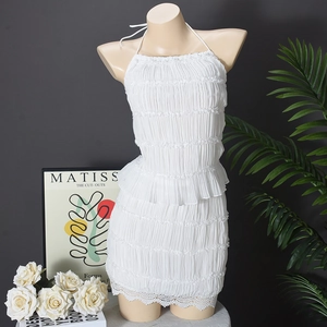 Detail of white halter neck pleated tiered dress featuring delicate lace trim at the hem