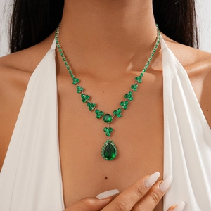 Detailed close-up of emerald green teardrop pendant necklace on model neckline