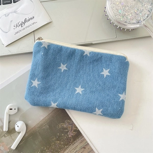 Detail of denim star print coin purse shown with laptop and travel accessories