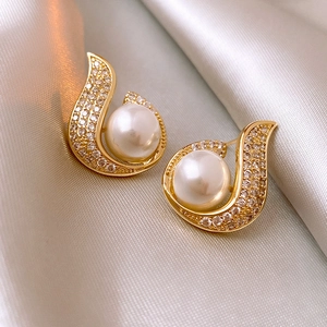 Macro detail of mermaid pearl fish tail earrings with sparkling zircon on silk