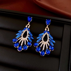 Macro shot of gold-plated drop earrings with blue teardrop crystals on black velvet