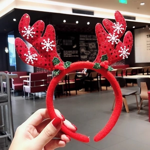 Detail of red Christmas antler headband with sequins, snowflakes and holly berry decor
