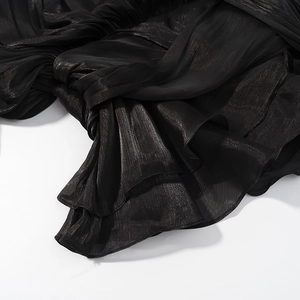 Gros plan sur un tissu plissé noir avec texture brillante et drapé élégant