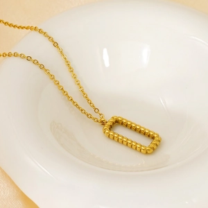 Elegant 18k gold rectangular rippled pendant necklace on a minimalist ceramic plate