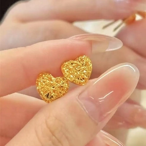 Macro shot of gold heart-shaped stud earrings with intricate hollow mesh texture detail