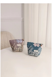 Detailed view showing the jacquard floral texture and gold flower zippers of two pouches.