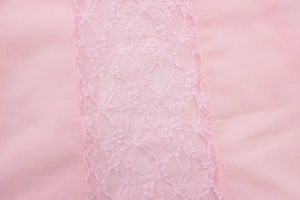Detailed macro view of pink fabric with intricate floral lace trim on a fishtail dress