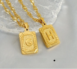 Detail of 18K gold-plated square letter pendants G and H on stainless steel chains