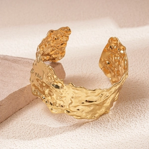 Detailed close-up of golden wide open cuff bracelet with irregular hammered texture