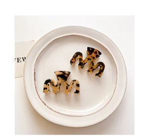 Macro shot of stylish tortoise shell mini hair claws on a decorative white ceramic plate