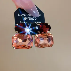 Macro view of S925 silver earrings featuring oval red and rectangular champagne stones