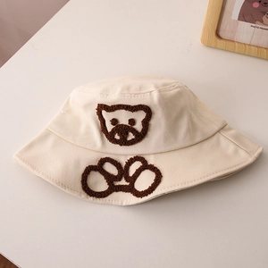 Détail du chapeau de soleil bébé avec broderie ours en peluche sur toile beige doux