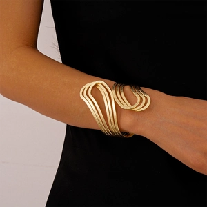 Detailed close-up of layered golden cuff bracelet with matte brushed metal texture