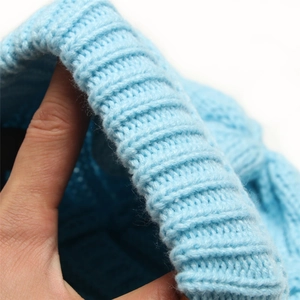 Close-up of light blue knitted beanie showing thick texture and elastic material