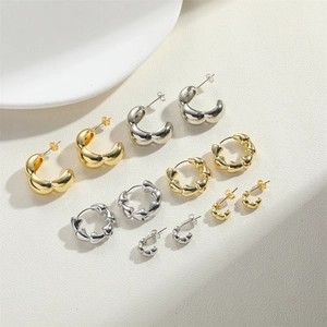 Flat lay of minimalist bamboo style C-shaped gold and silver earrings on white background