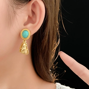 Gros plan de boucles d'oreilles dorées vintage avec turquoise et pendentif éventail