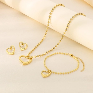 Detailed close-up of golden heart pendant jewelry set with elegant bead chain on beige paper