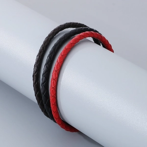Gros plan de bracelets en cuir tressé rouge, noir et marron avec fermoirs magnétiques