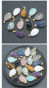 Detail of teardrop natural crystal pendants with gold-plated edges in various gemstones