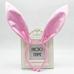 Pink satin bunny ears headband displayed on a vintage frame for Easter party decor