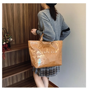 Brown gloss Tyvek tote bag with white text held by a model for a stylish casual look
