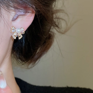 Close-up of elegant bow earrings with pearls and crystals worn on a female model