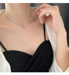 Close-up of minimalist hollow heart pendant necklace in silver on a model neckline