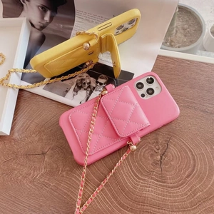 Detailed view of pink and yellow quilted phone cases with metal chain straps on wooden desk