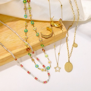 Close-up of colorful floral enamel necklaces and gold star pendants on silk