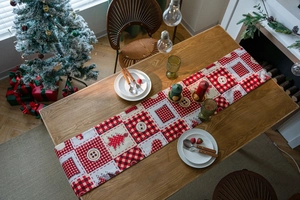 Detailed top view of a red and black plaid Christmas table runner on a wooden dining table