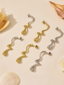 Détail de boucles d'oreilles vagues bicolores dorées et argentées au design ondulé