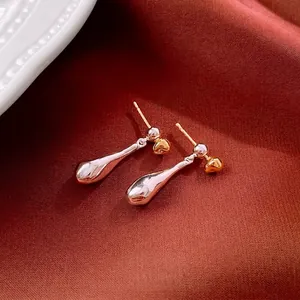 Luxury gold and silver plated teardrop earrings with heart detail on red fabric background