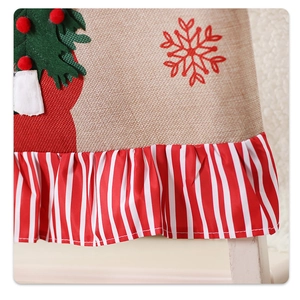 Detail of Christmas chair cover with linen texture, green tree motif and red striped lace