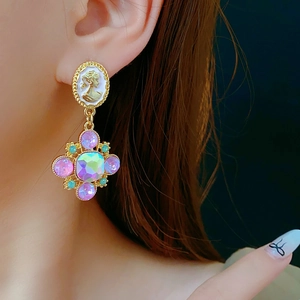Close-up of vintage gold earrings with colorful crystals worn by a model