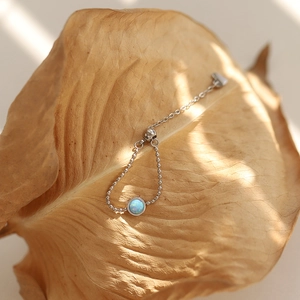 Detailed view of an adjustable opal bead ring with a heart charm on a dried leaf