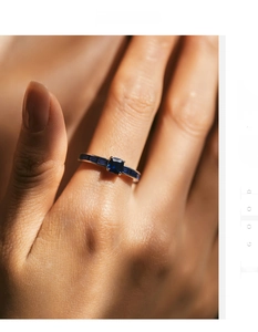 Detailansicht eines blauen Saphirrings mit Baguetteschliff-Steinen auf Silberband