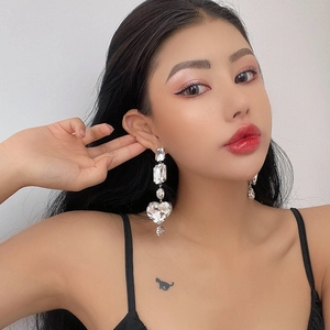 Elegant long geometric heart drop earrings with sparkling rhinestones worn by a model